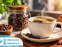 قهوه تازه دم شده در فنجان سرامیکی کنار دانه های قهوه و کروسان در فضایی گرم و دلنشین.