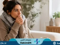 خانمی که در فضای گرم خانه دست های سرد خود را برای گرم شدن نزدیک صورت نگه داشته است و نشان دهنده احساس سردی دست ها و پاها است.