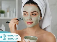 خانمی در حال استفاده از ماسک خاک رس صورت در روتین مراقبت از پوست در فضای آرام و تمیز حمام.