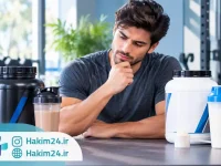 مرد ورزشکار در حال مقایسه مکمل های گینر و پروتئین وی در سالن ورزشی